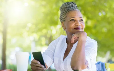 an elderly woman poses with cell phone in hand